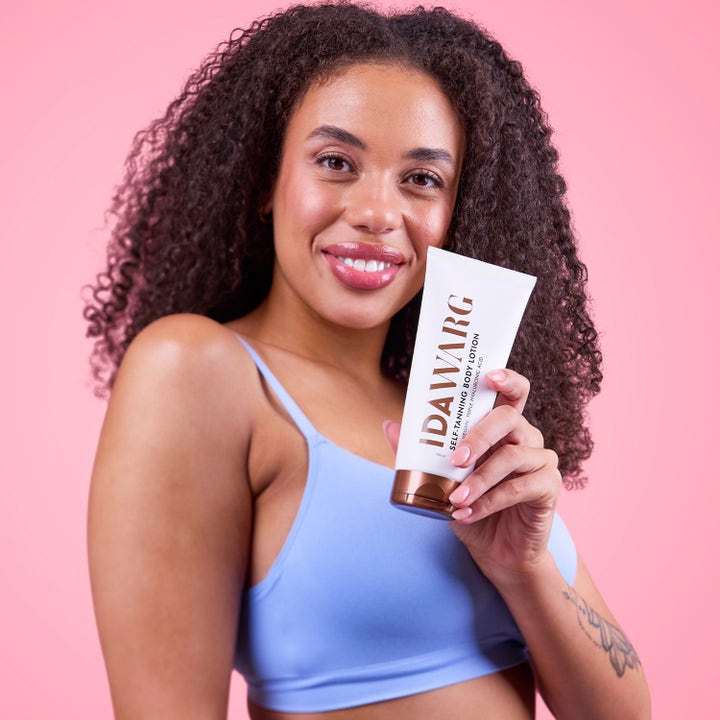IDA WARG Beauty Self Tanning Body Lotion 200 ml giver glød i hvid tube holdt af smilende kvinde