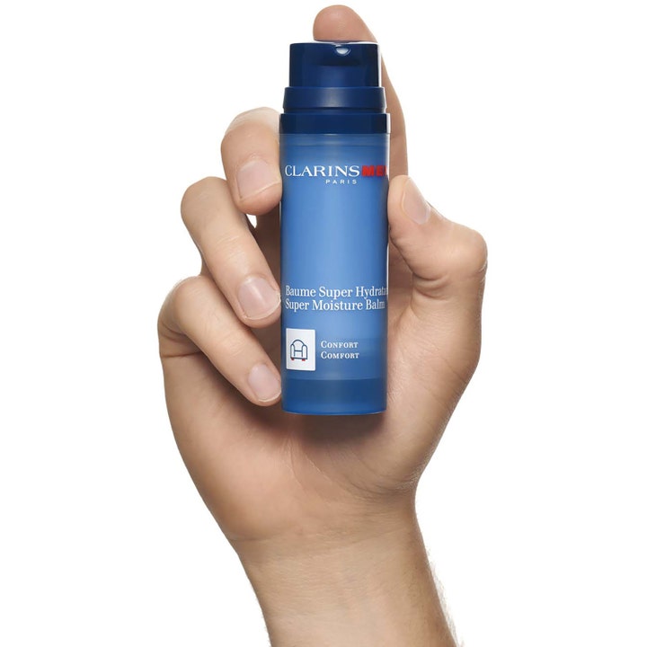 Clarins Men Super Moisture Balm 50 ml fugtgivende ansigtscreme i blå pumpeflaske holdt i en mands hånd