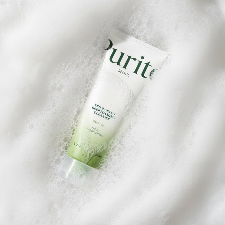 Purito From Green Deep Foaming Cleanser 150 ml ansigtsrens i hvid tube holdt af en hånd i et lyst badeværelse