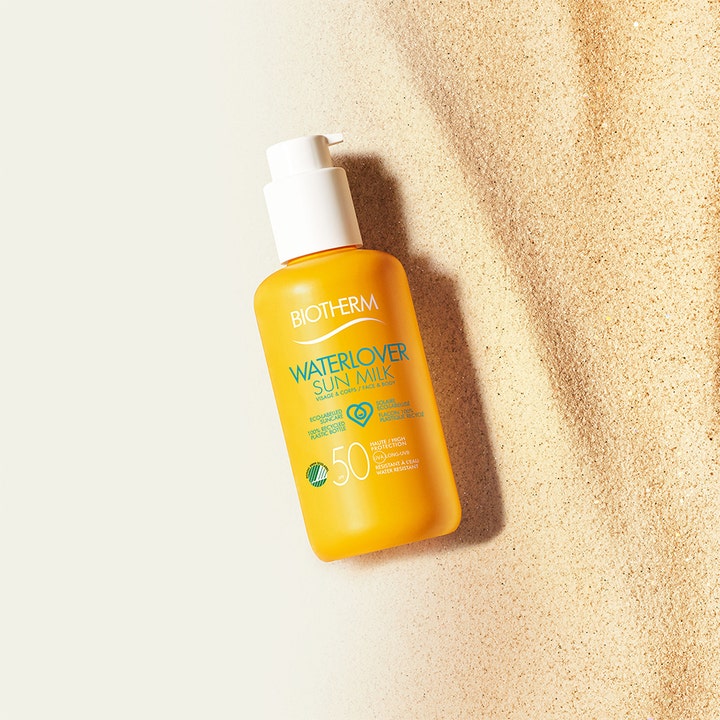 Biotherm Waterlover Sun Milk SPF50 200 ml solcreme i gul flaske med hvid pumpe placeret i lyst sand.