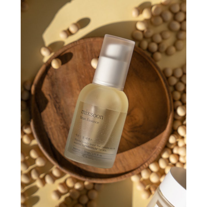 Mixsoon Bean Essence 30 ml fugtgivende essence i frostet flaske på en træbakke med sojabønner.
