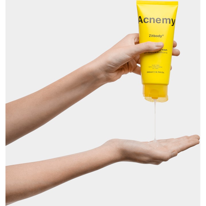Niche Beauty Lab Acnemy Zitbody 200 ml rensende bodywash mod urenheder i gul tube der trykker klar gel ud i en hånd