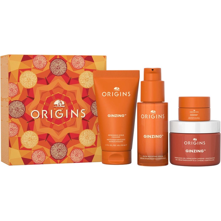 Origins GinZing 4 dele energigivende hudpleje med koffein i orange krukker og tuber foran en mønstret gaveæske