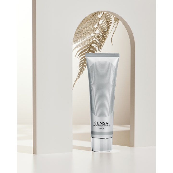 Sensai Cellular Performance Mask 100 ml fugtgivende ansigtsmaske i sølvtube foran en bue og et smukt tørret blad