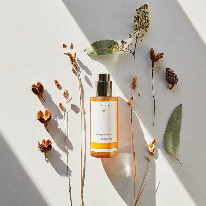 Dr. Hauschka Facial Toner 100 ml styrkende ansigtstoner i glasflaske omgivet af tørrede planter og blade.