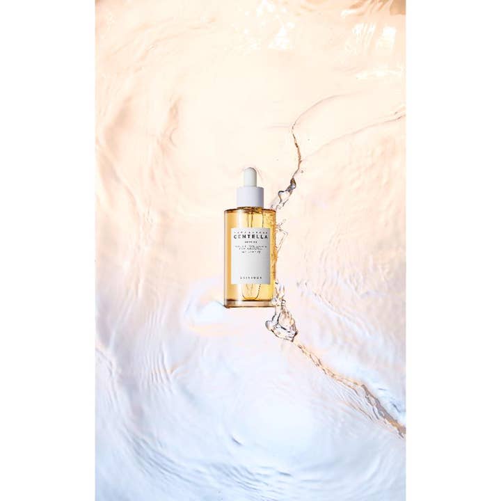 SKIN1004 Madagascar Centella Ampoule 100 ml beroligende serum i klar glasflaske omgivet af vandkrusninger