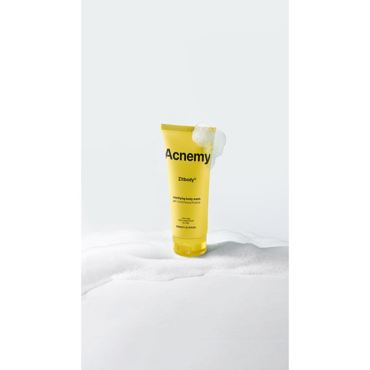 Niche Beauty Lab Acnemy Zitbody 200 ml rensende kropsvask i gul tube placeret i blødt hvidt skum