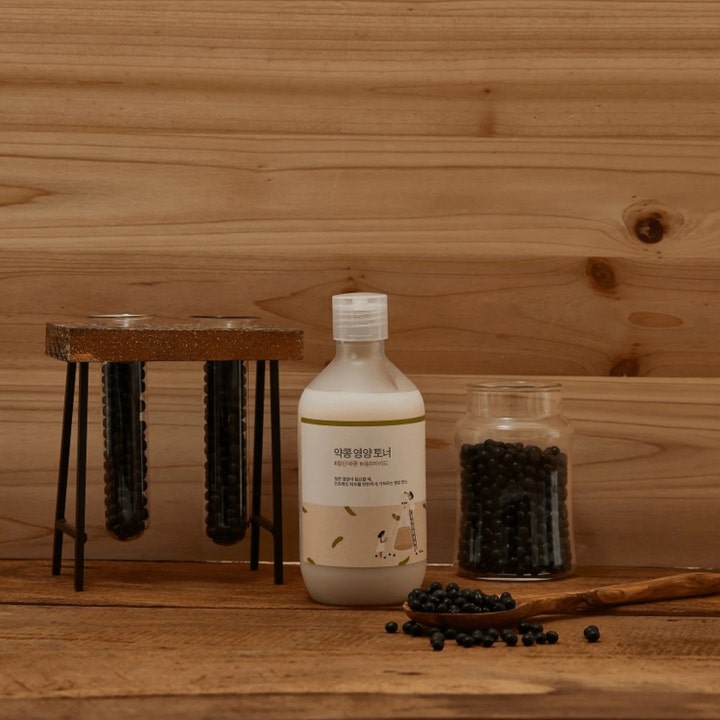 Round Lab Soybean Nourishing Toner 300 ml nærende toner i hvid flaske med sorte sojabønner på træoverflade