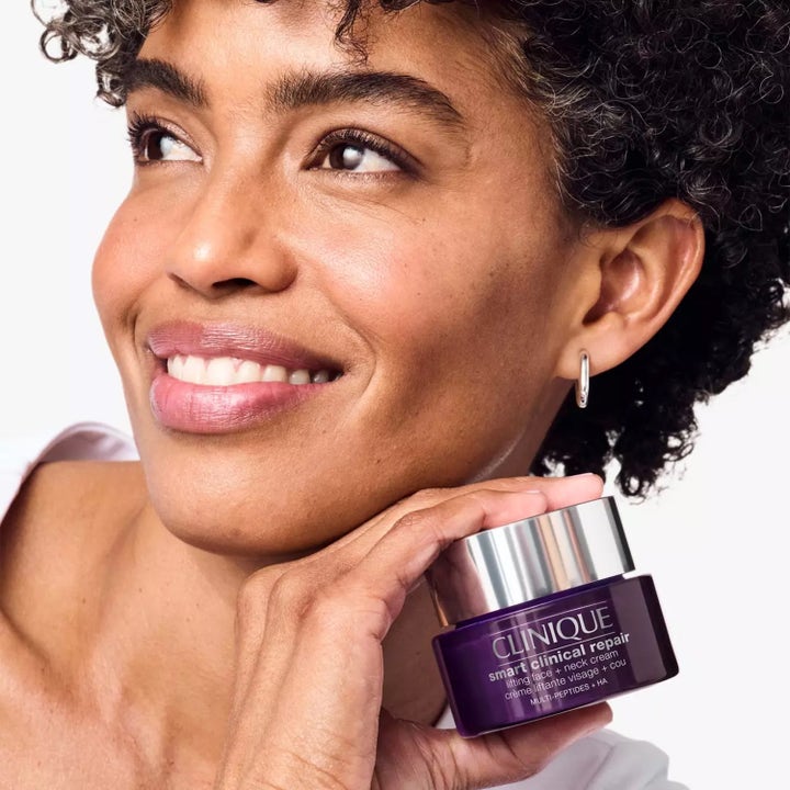 Clinique Smart Clinical Repair 75 ml opstrammende ansigtscreme i lilla krukke holdt af en smilende kvinde.