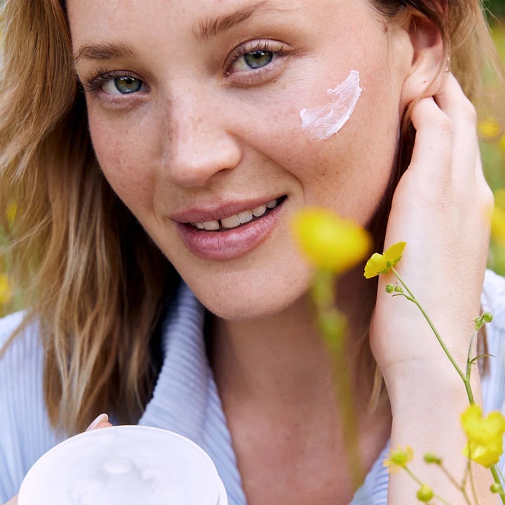 NIVEA Soft 200 ml fugtgivende creme på en smilende kvindes kind i en blomstermark med gule blomster.