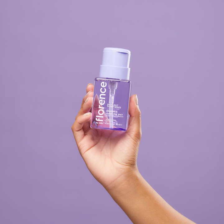 Florence by Mills Spotlight Toner Series 2 185 ml i klar lilla flaske holdt af en hånd mod lilla baggrund