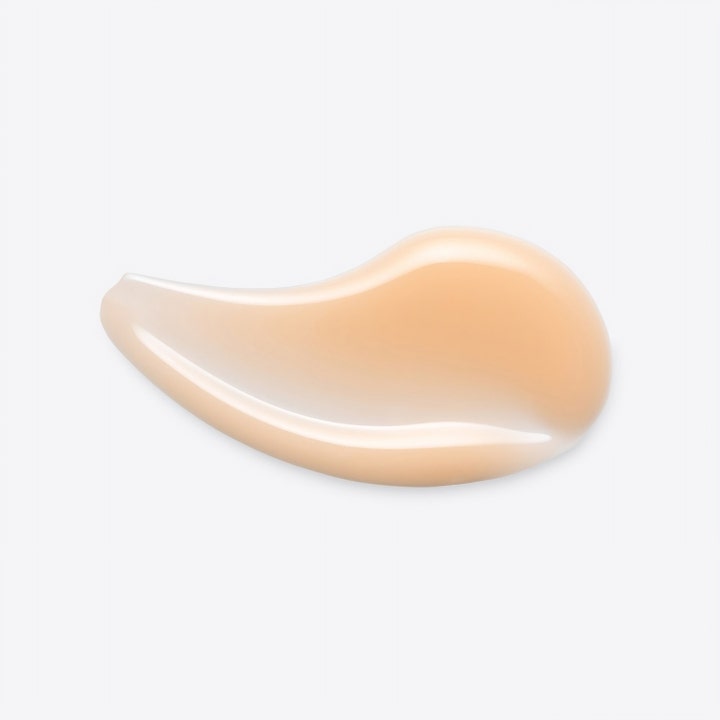 Origins GinZing Into the Glow Brightening Serum 30 ml viser en cremet lys ferskenfarvet tekstur mod hvid baggrund