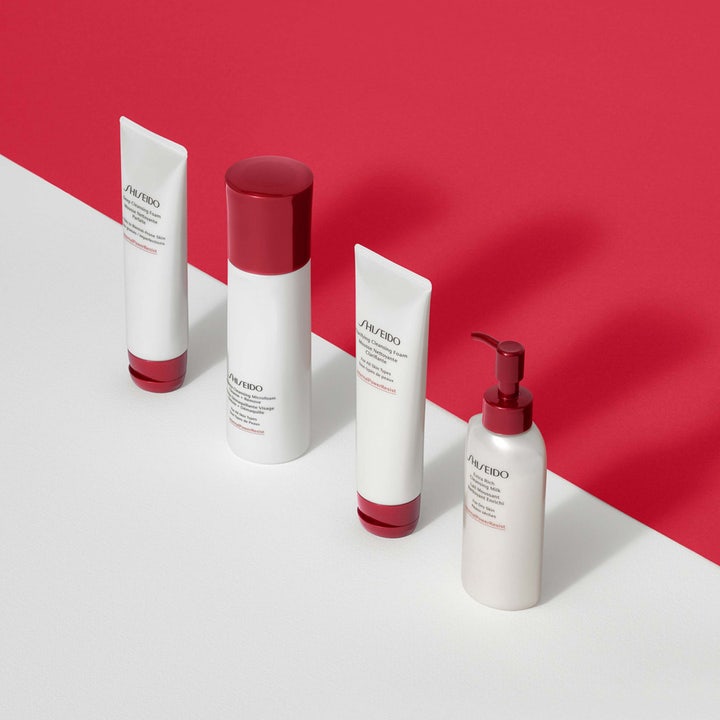 Shiseido Complete Cleansing Microfoam 180 ml rengøringsskum i hvid flaske med rødt låg på rød og hvid baggrund