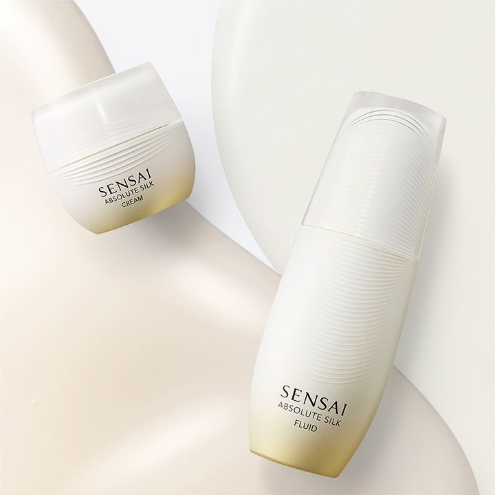 Sensai Absolute Silk Fluid 80 ml fugtgivende ansigtspleje i hvid og guld flakon vist sammen med en krukke.