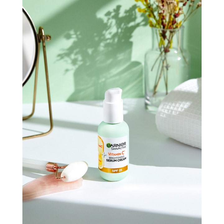 Garnier Skin Active Vitamin C 2-i-1 Serum Cream 50 ml dagcreme med SPF 25 i pumpeflaske vist med en ansigtsrulle.