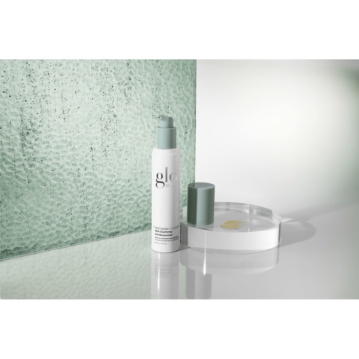 Glo Skin Beauty BHA Clarifying Gel Moisturizer 50 ml ansigtscreme i hvid pumpeflaske med gul gel på en glasbakke.