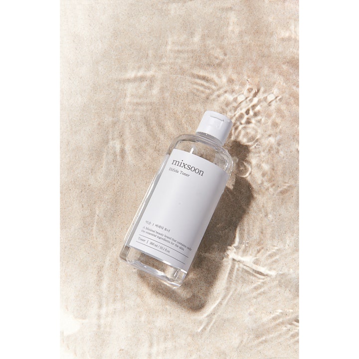 Mixsoon Bifida Toner 300 ml styrkende ansigtsvand i klar plastflaske på sandbund i lavt vand