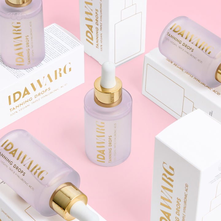 IDA WARG Beauty Tanning Drops 45 ml giver glød i lilla glasflasker med guldskruelåg på rosa baggrund