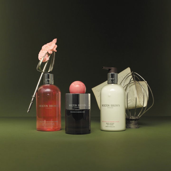 Molton Brown Delicious Rhubarb &amp; Rose Body Lotion 300 ml fugtgivende lotion i hvid pumpeflaske ved siden af et piskeris.