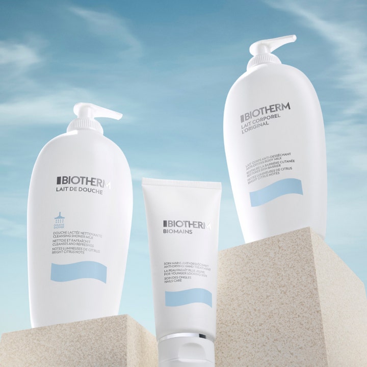 Biotherm Lait Corporel 400 ml fugtgivende bodylotion hvide flasker og tube på stenblokke mod en blå himmel