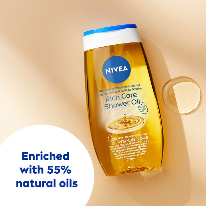 NIVEA Rich Caring Shower Oil 200 ml plejende duscholie med 55% naturlige olier ved siden af en klar oliedråbe