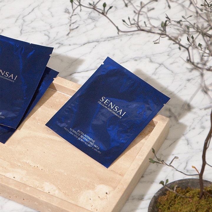 Sensai Cellular Performance Extra Intensive 10 Minutes Revitalizing Pads øjenmaske i blå breve på en beige bakke