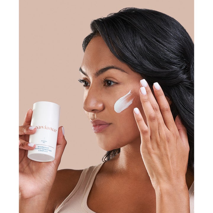 Exuviance Overnight Transformation Complex 50 g fugtgivende natcreme påføres på kinden fra hvid pumpeflaske.
