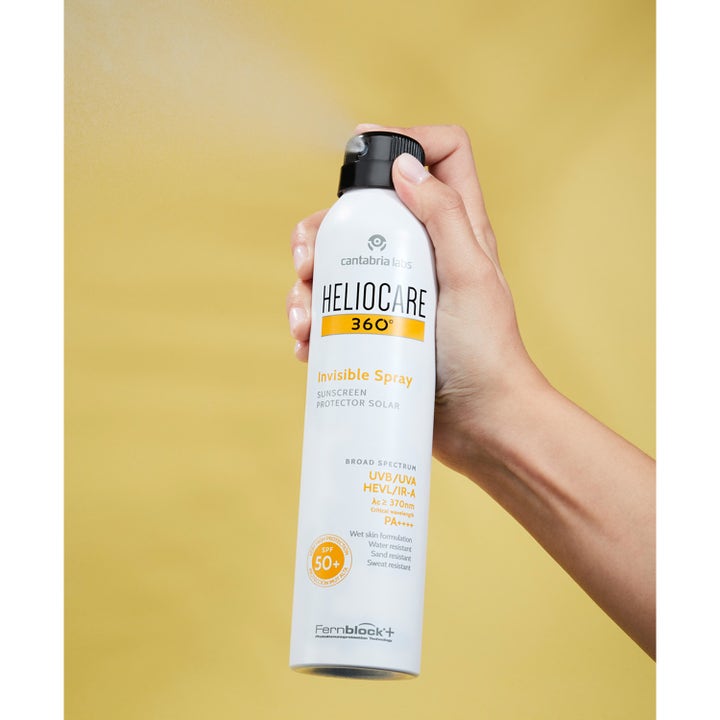 Heliocare Invisible Spray SPF 50+ 200 ml solbeskyttelse i hvid sprayflaske der sprayer en fin tåge mod gul baggrund.