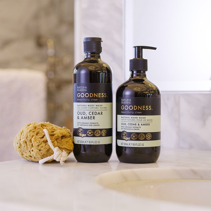 Baylis & Harding Goodness Body Wash 500 ml vegansk kropssæbe i mørk flaske vist med en natursvamp i et lyst badeværelse
