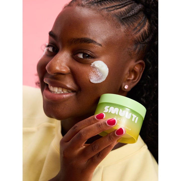 Smuuti Skin Pear Cleansing Balm 100 ml ansigtsrens påført en smilende kvindes kind fra en lysegrøn krukke