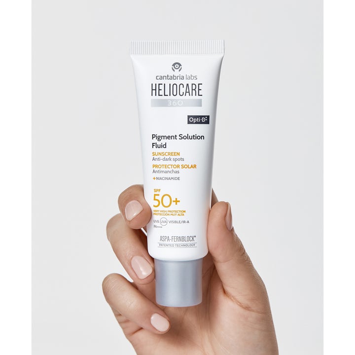 Heliocare Pigment Solution Fluid SPF 50+ 50 ml solcreme mod pigmentpletter i hvid tube med niacinamid holdt i en hånd