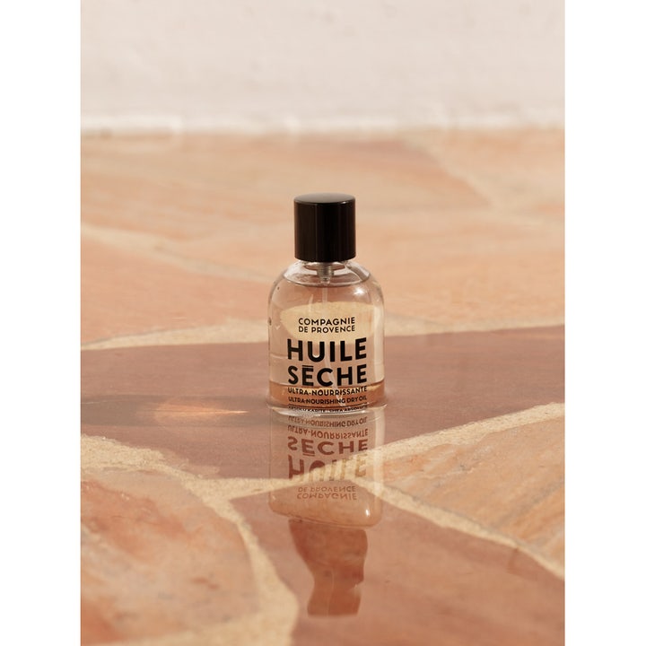 Compagnie de Provence Ultra Nourishing Dry Oil Shea Butter 100 ml nærende kropsolie i glasflaske på stenoverflade