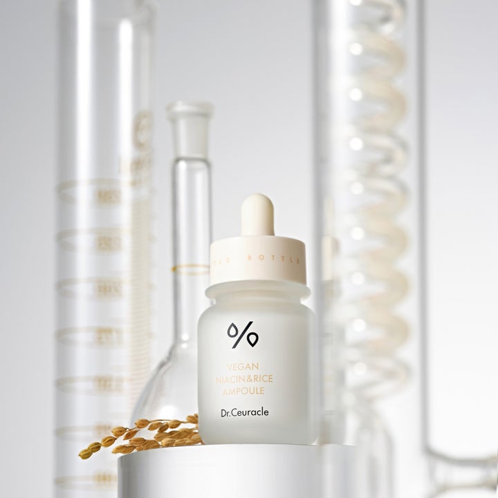 Dr. Ceuracle Vegan Niacin & Rice Ampoule 30 ml serum i hvid glasflaske med pipette foran laboratorieglas.