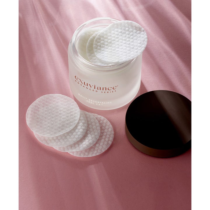 Exuviance Daily Resurfacing Peel 58 ml peeling pads i frostet krukke med hvide teksturerede rondeller på lyserød baggrund