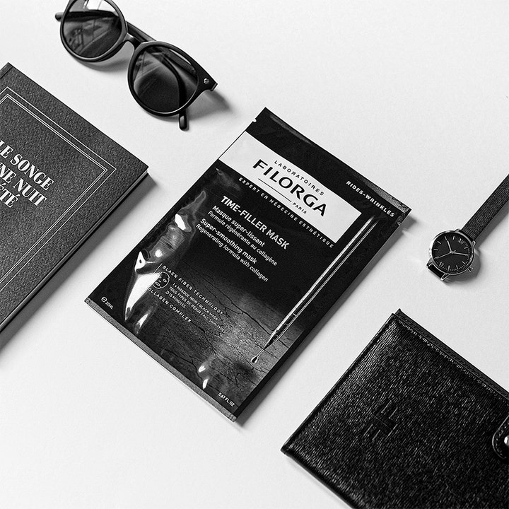 Filorga Time-Filler Mask 23 g udglattende sheet mask med kollagen i sort emballage ved siden af solbriller og ur.
