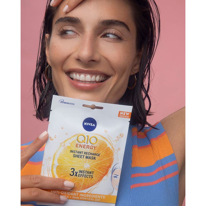 NIVEA Q10 Energy Sheet Mask 1 stk opfriskende ansigtsmaske holdt af smilende kvinde på lyserød baggrund