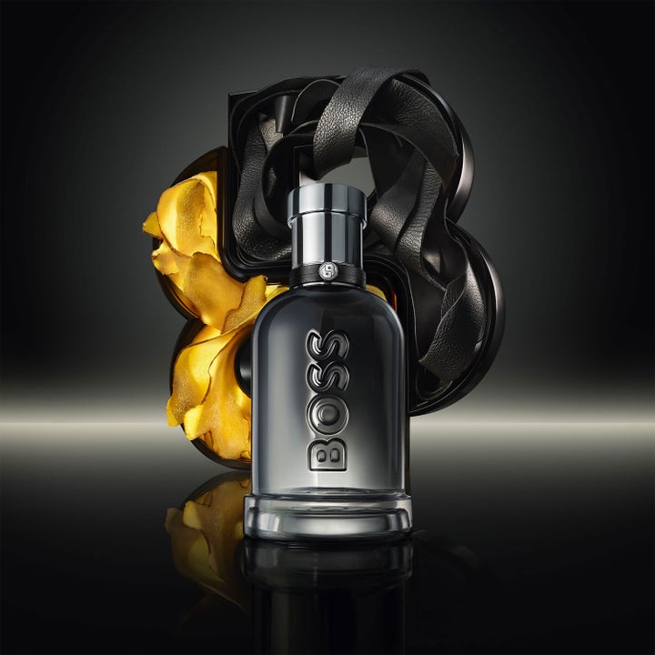 Hugo Boss Bottled Beyond 200 ml showergel i mørk glasflaske foran læder og gyldne elementer