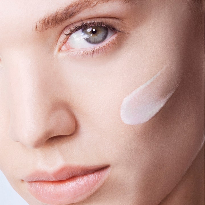 Lancôme UV Expert Supra Screen SPF50 40 ml solcreme viser en let lyserød tekstur påført en kvindes kind
