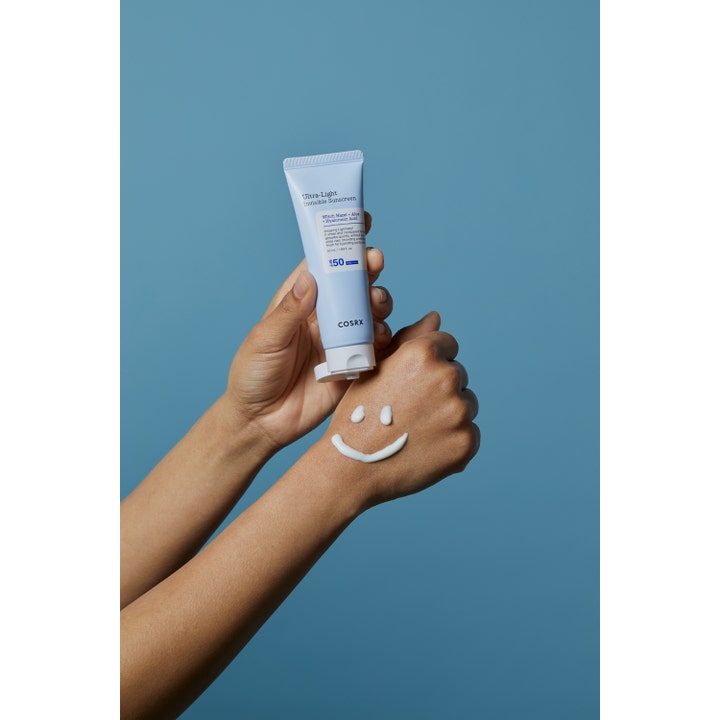 COSRX Ultra-Light Invisible Sunscreen 50 ml fugtgivende ansigtssolcreme i lyseblå tube med creme formet som et smil
