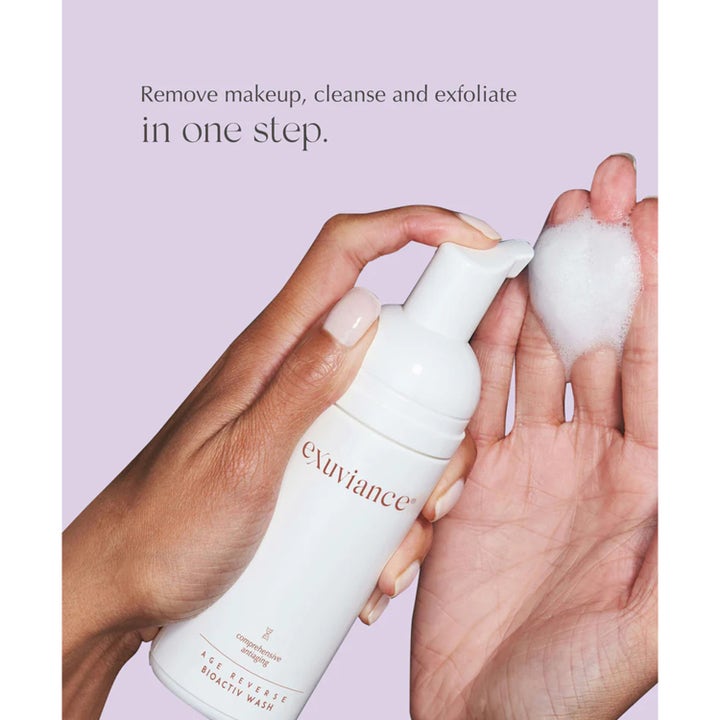 Exuviance Age Reverse BioActiv Wash 125 ml eksfolierende ansigtsrens i hvid pumpeflaske med blødt skum i en hånd
