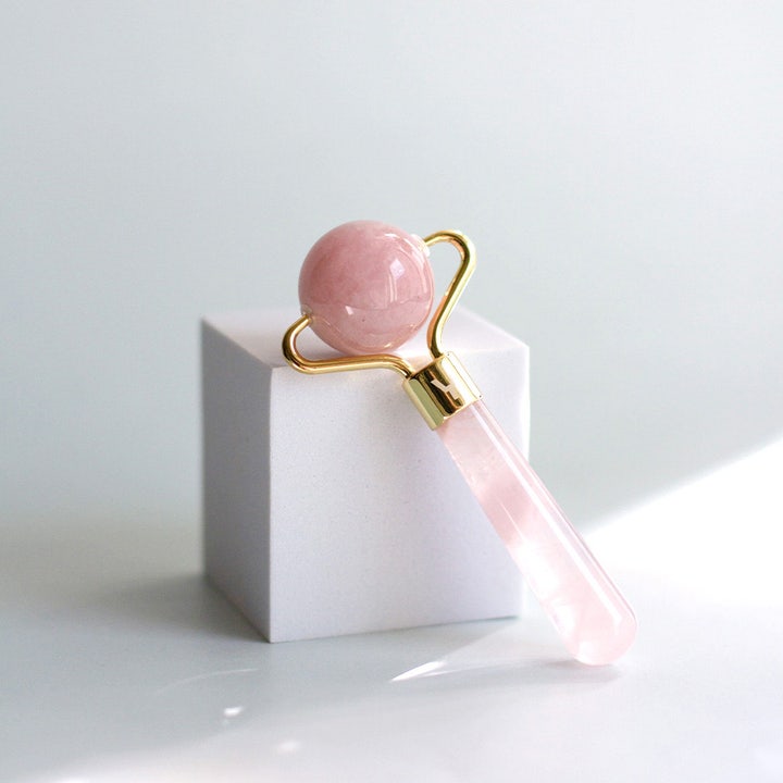 Sense of Youty Eye Massage Roller Rose Quartz ansigtsrulle i rosa kvarts med gulddetaljer på hvid blok