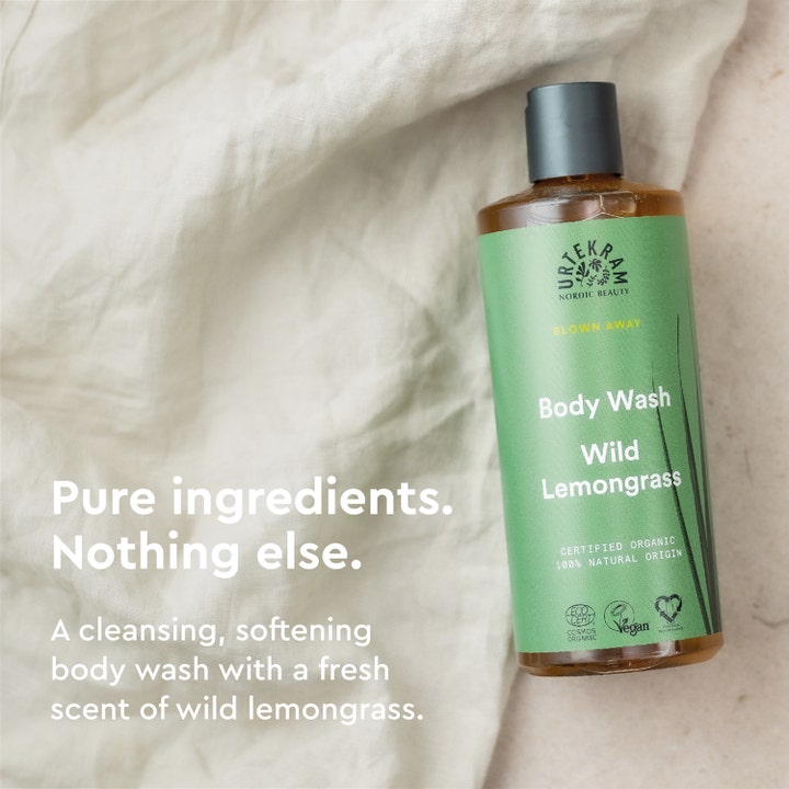 Urtekram Wild Lemongrass Body Wash 500 ml i flaske med grøn etiket liggende på et lyst tekstil