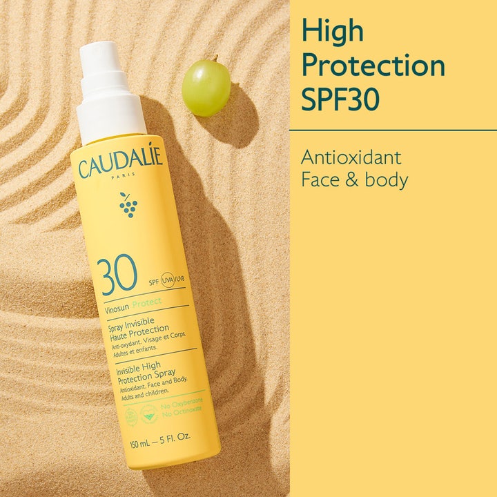 Caudalie Vinosun High Protection Spray SPF30 150 ml antioxidant solcreme i gul sprayflaske i sand med en vindrue