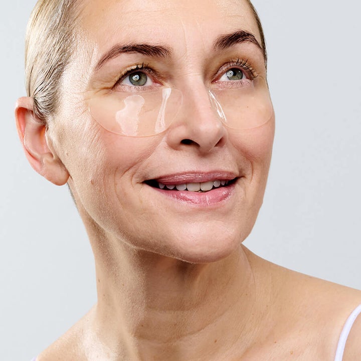 Currentbody Skin Hydrogel Eye mask 2 g fugtgivende eye patches vist som gennemsigtige masker på en smilende kvinde
