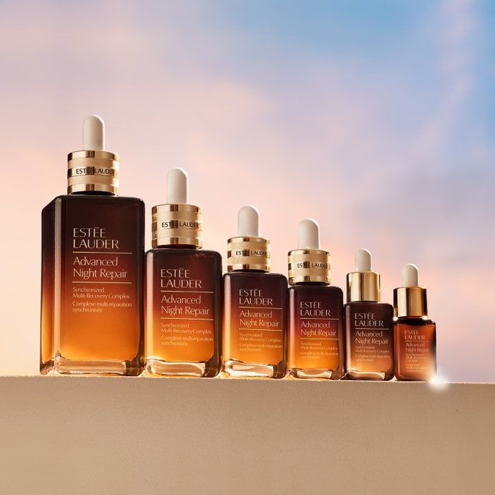 Estée Lauder Advanced Night Repair 20 ml serum genopbygger huden vist i brune glasflasker med guld mod en aftenhimmel.
