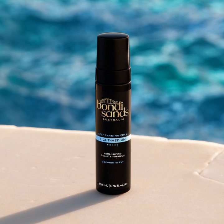 Bondi Sands Self Tanning Foam Light Medium 200 ml selvbruner mousse i sort flaske ved en blå poolkant