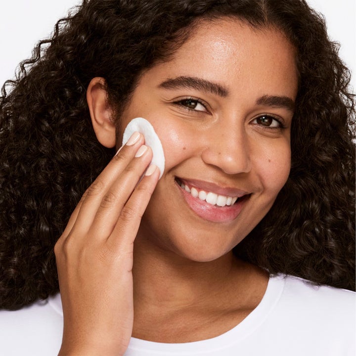 Clinique Clarifying Lotion 3 487 ml toner påføres med vatrondel af smilende kvinde for en frisk hud.