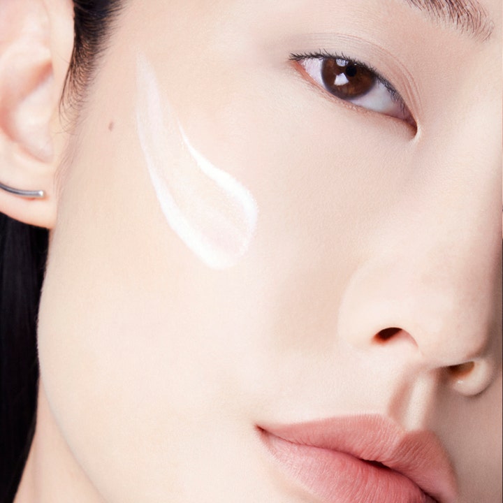 Lancôme UV Expert Supra Screen SPF50 40 ml beskyttende solcreme viser hvid flydende tekstur på en kind