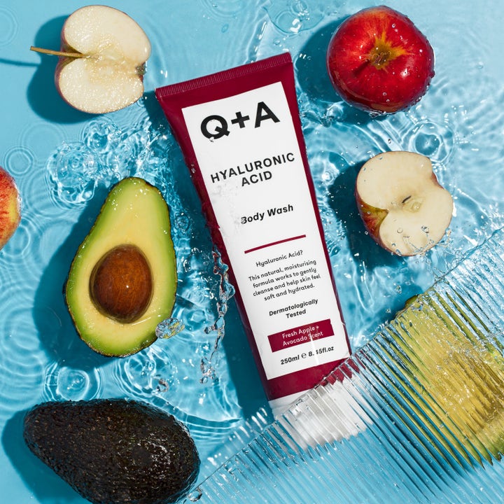 Q+A Hyaluronic Acid Body Wash 250 ml fugtgivende bodyshampoo i rød tube omgivet af friske æbler og avocado i vand