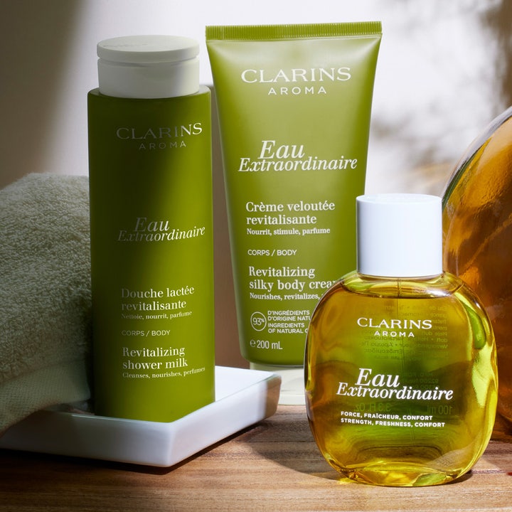 Clarins Eau Extraordinaire Revitalizing Shower Milk 200 ml plejende kropsvask i grøn flaske vist med creme og duftvand